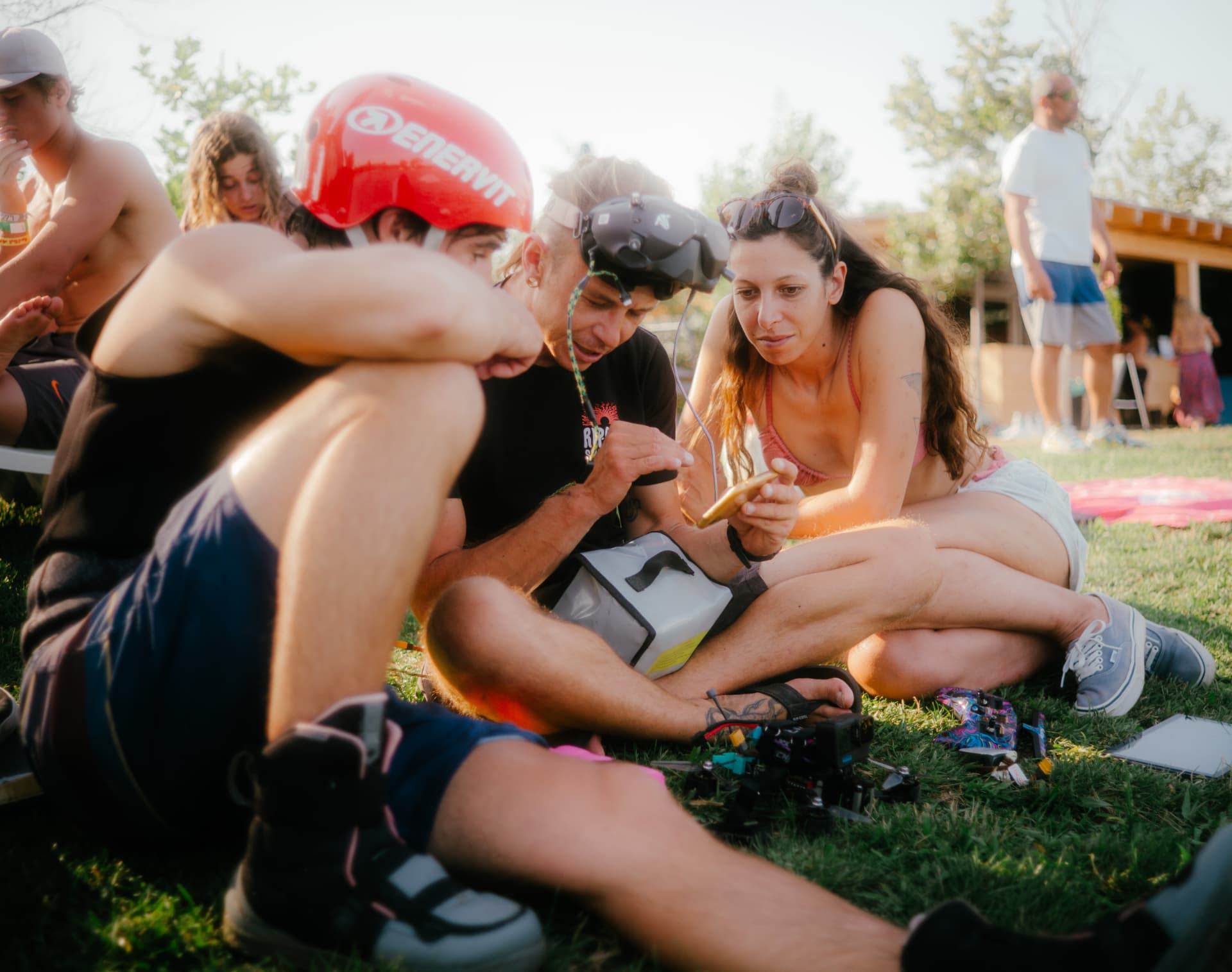 Riders sharing photos and stories on the grass at a cable park